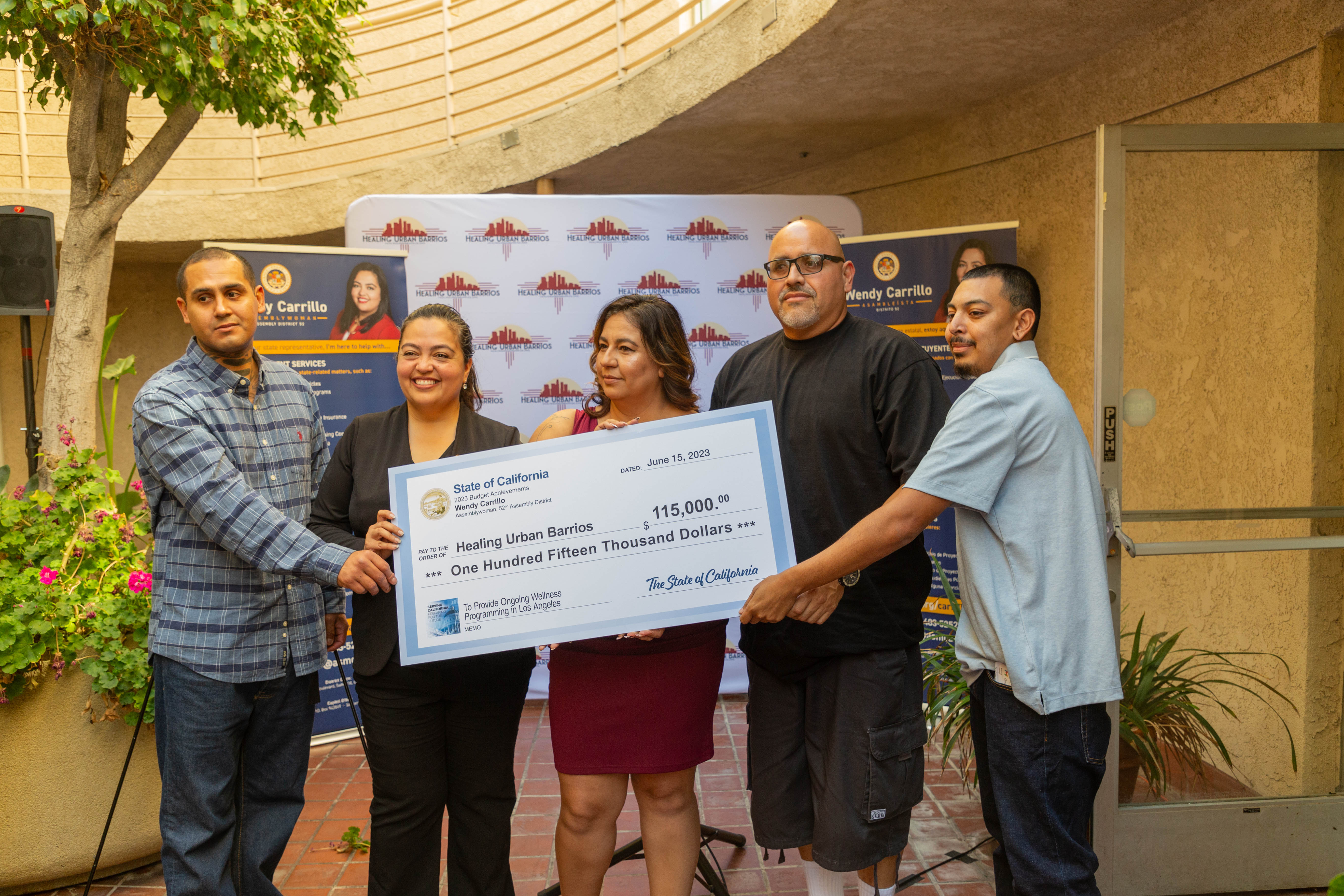 Assemblywoman Wendy Carrillo holds large symbolic check of $115,000 with Healing Urban Barrios