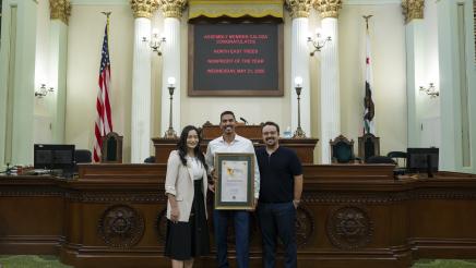 Assemblymember Jessica Caloza stands inside the California State Assembly Chamber with two representatives from North East Trees.